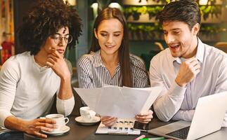 Millennial business team discussing project in cafe, reading contract terms and conditions during business lunch, free space photo