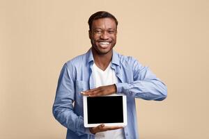 Great App. Smiling African American Man Showing Empty Tablet Screen On Yellow Background In Studio. Mockup photo