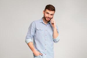 Glad to hear you. Portrait of smiling man talking on phone on studio background, panorama, copy space photo