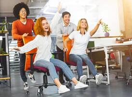 Chair race competition. Cheerful millennials riding on office furniture, having fun at work, panorama, empty space photo