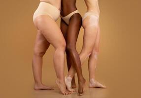 Every Body Is Beautiful. Tree women with different race and body sizes posing in underwear over beige background, cropped image with free space photo