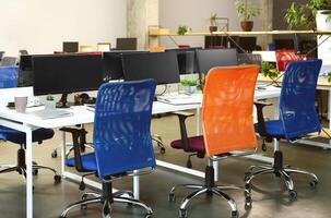 Creative interior of cozy co-working space. Bright colorful chairs and desks with modern computers for work, empty space photo