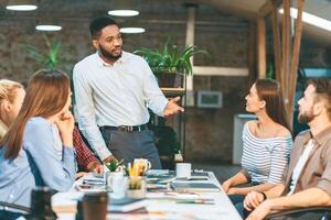 A man stands confidently in front of a diverse group of individuals, engaging in a discussion or presentation. photo