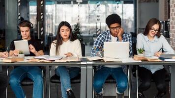 Students using different gadgets studying in university library and preparing for exams photo
