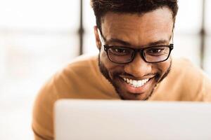 Happy African Businessman Making Call To Family Using Laptop During Rest Break At Work, Close-Up photo