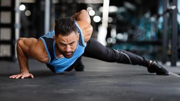 Strength exercise. Muscular man doing push ups on on hands in gym, panorama photo