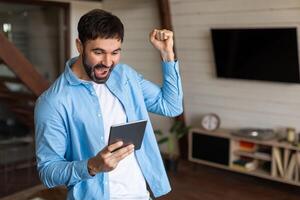 A man wearing a blue jacket is seen holding a tablet device in his hands. The man appears focused on the tablet screen as he interacts with the device. photo