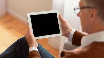 Unrecognizable Elderly Man Using Digital Tablet With Blank Screen Sitting At Home. Panorama, Selective Focus, Mockup photo