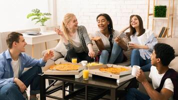 A diverse group of multiethnic friends are gathered around a wooden table. They are enjoying slices of hot pizza, engaged in casual conversation and laughter. photo