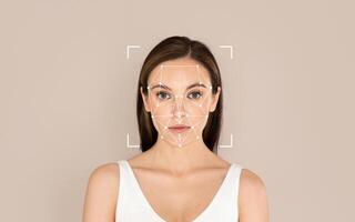 A woman stands calmly as facial recognition technology is applied to analyze her features with a simple background. photo