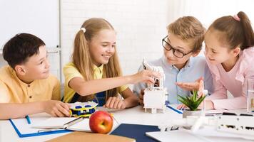 Four children, two boys and two girls, are working together on a robotics project in a classroom setting. They are all smiling and appear to be engaged in the task at hand photo