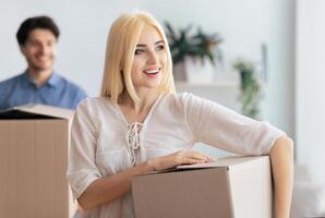 Husband And Wife Carrying Moving Boxes Into New Flat Or House Changing Apartment. Selective Focus photo