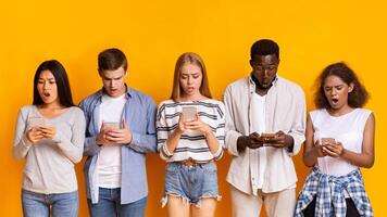 Problematic smartphone use. Multiracial group of teenagers using mobile phones over yellow background, panorama photo