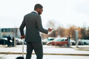 Businessman Ordering Taxi, Using Mobile Phone App, Arriving At Airport photo