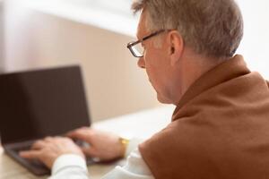 Unrecognizable Senior Gentleman Working On Laptop Sitting At Workplace. Selective Focus, Back View photo