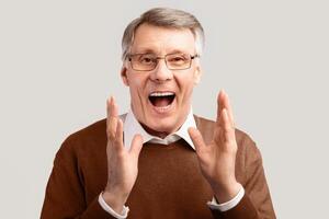 Excited Senior Gentleman Shouting Posing Over Gray Studio Background, Looking At Camera. Excitement And Joy photo
