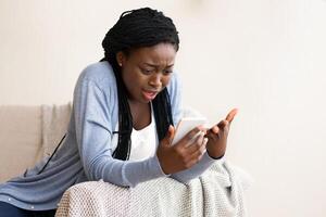 Connection problems. Frustrated afro girl having issues with smartphone at home, disappointed with no signal, free space photo