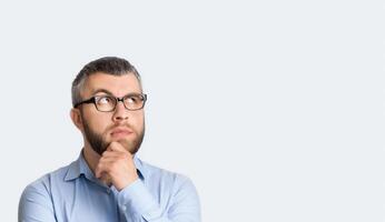 A man wearing glasses and a blue shirt is standing in the photo. He appears to be looking straight ahead with a neutral expression on his face, copy space photo