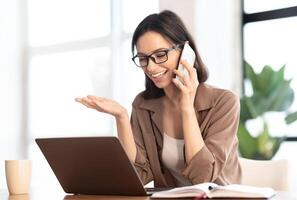Informal Call. Happy young woman in glasses calling her friend, talking and asking about something, using laptop photo
