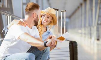 Loving couple in airport using travel app on smartphone, waiting for departure, panorama with copy space photo