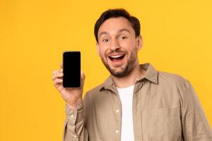 A man is holding up a cell phone in front of his face, focusing on the screen. He appears to be engaged with the device, showing nice app or online offer photo