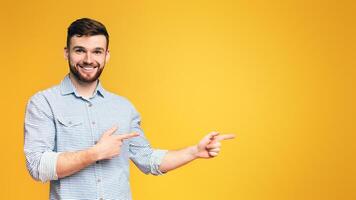 Stylish redhead bearded millennial man pointing away at empty space, showing new offer on orange background photo