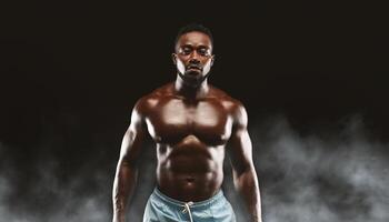 A muscular man poses with his arms at his sides in front of a dark background with smoke. photo