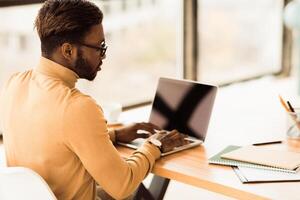 Checking E-mail. Afro businessman learning, working on laptop, using applications on netbook, copyspace photo