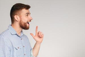 Young excited man having good idea and feeling happy about that, grey studio background, panorama, copy space photo
