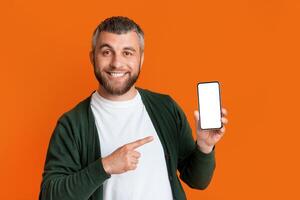 A man is standing, holding a smart phone in his hand. He is looking at the screen intently, possibly scrolling or texting. The background is unclear, focusing on the man and the device in his hand. photo
