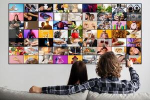 A couple is sitting on a couch, watching television. The screen is displaying multiple channels, each with a different image or . The couple is relaxed and enjoying their time together. photo