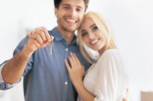 A happy couple stands together, the man holding up a set of keys, symbolizing their new home. photo