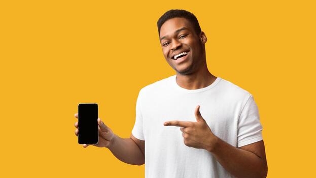 Awesome Application Or Website. Black man showing blank cellphone screen for advertising text, empty space, mock up photo