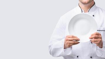 Culinary Recipes. Unrecognizable Chef Man Holding Plate Standing Over White Studio Background. Cropped, Panorama With Empty Space photo