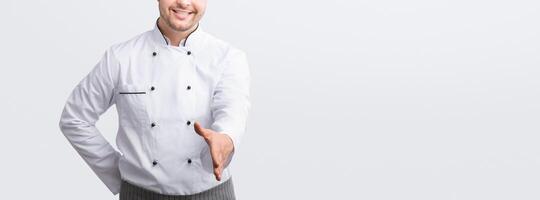 Male Chef Stretching Hand For Handshake Greeting Smiling To Camera Standing Over White Studio Background. Panorama photo