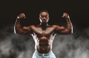 A muscular man flexes his biceps, showcasing his strength and physique against a dark background with subtle smoke effects. photo