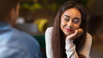 africano americano niña es sentado a un mesa en un restaurante, curioso atentamente a un chico quien es a través de desde su. el chico parece inconsciente de su mirada como él come. foto