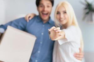 Home Owners. Excited Couple Showing Keys Hugging In New House. Shallow Depth, Selective Focus photo