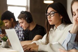 Female student typing on laptop, studying in library and preparing for final exam photo