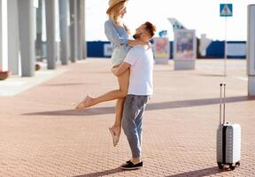 Couple meeting after long time, hugging near airport building, free space photo