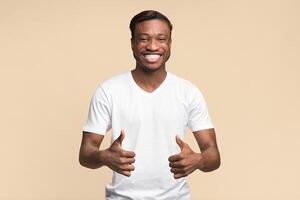 Cheerful Afro Man Gesturing Thumbs Up With Both Hands Posing Over Yellow Studio Background. Like Concept. photo