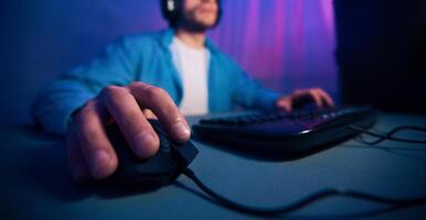 A close-up image of a gamers hand using a computer mouse while playing a game on their desktop. The focus is on the hand and the mouse, cropped photo