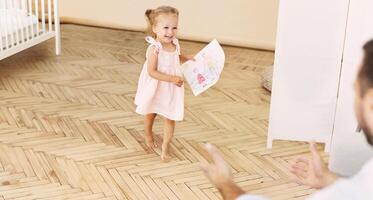 Happy little child running to father and holding a drawing with Daddy and Me text photo