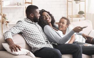 Joyful black family having fun together, relaxing on sofa at home. photo