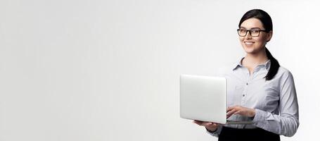 A smiling businesswoman in a white shirt holds a laptop in front of a white background. photo