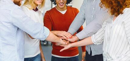 A diverse group of individuals standing together in a circle, each holding hands with the person next to them. They are united in a gesture of unity and solidarity, cropped, panorama photo