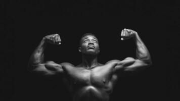 A black and white photo of a man flexing his biceps, looking upward against a dark background.