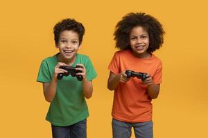 Two African American boys, both holding game controllers in their hands, seem engrossed in an intense gaming session. Their faces show concentration and excitement as they focus on the screen. photo