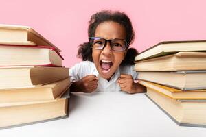 Stressed Black Elementary Student Girl Yelling Sitting Between Book Stacks In Studio Over Yellow Background. Schoolwork Overload Concept photo