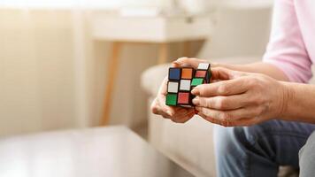 Kharkiv, Ukraine - January 14, 2019. Old woman holding Rubik's cube and playing with it at home, Rubik's cube invented by Hungarian architect Erno Rubik in 1974, free space photo